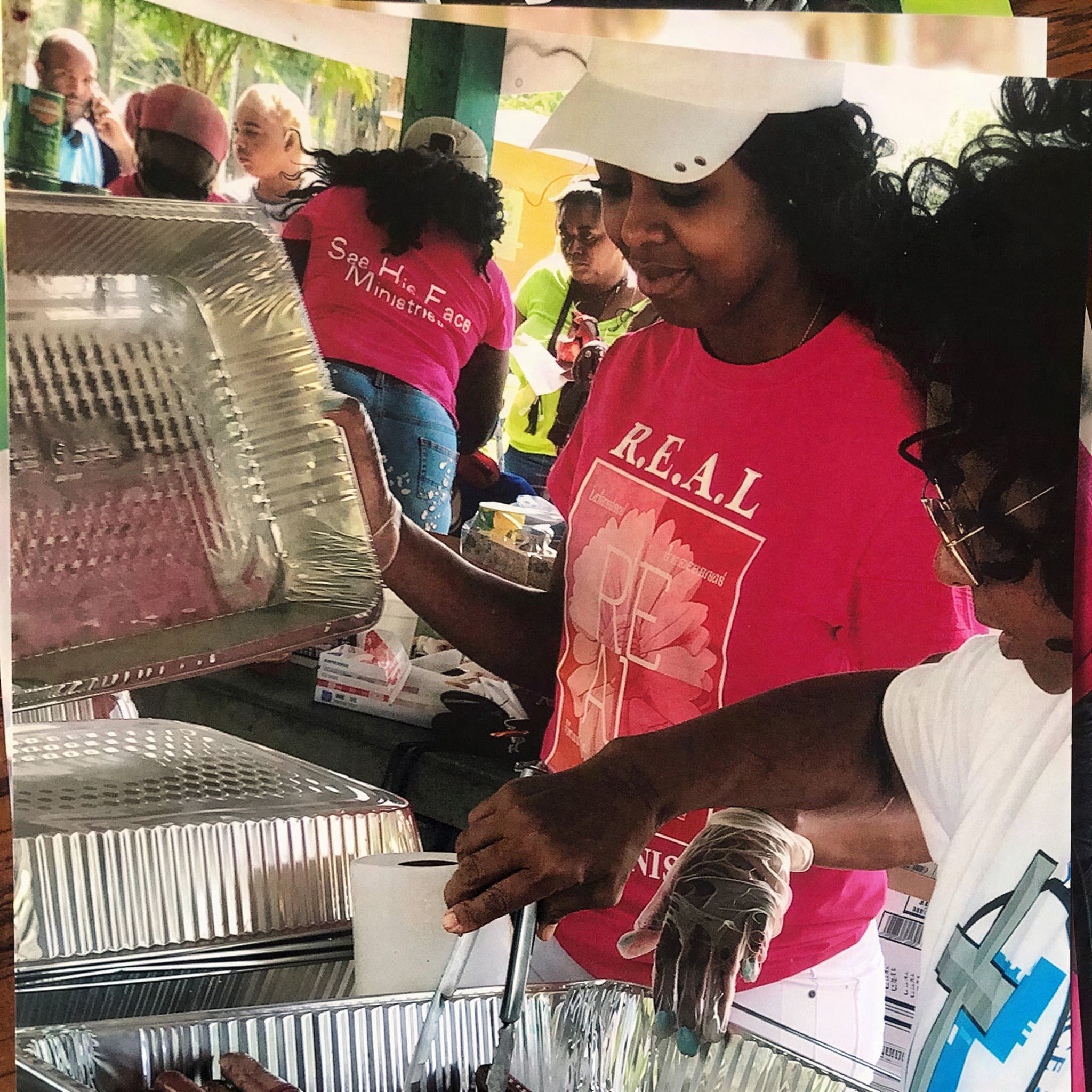 Volunteers in R.E.A.L. Women Ministry shirts serving hot food at a Seeds of Kindness outreach in Fort Myers
